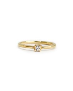 a yellow gold ring with a single diamond on the front and side, set against a white background