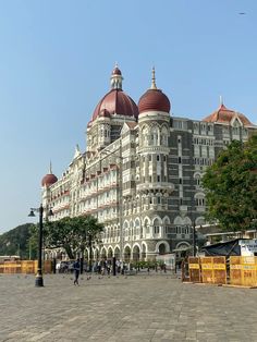 a large white building with red domes on it's roof and people walking around