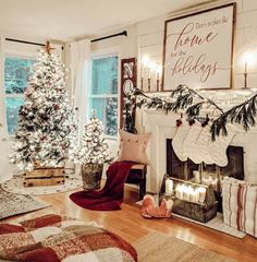 a living room decorated for christmas with stockings on the fire place and trees in pots