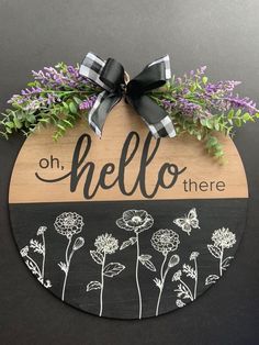 a wooden sign that says hello there with flowers on it and a bow hanging from the front