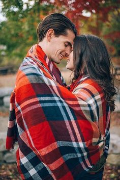 a man and woman wrapped in a blanket are smiling at each other while they hug