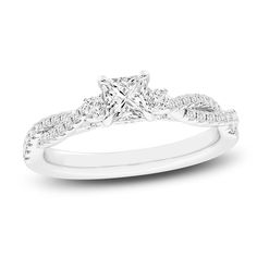 a white gold ring with a princess cut diamond in the center and pave set shoulders