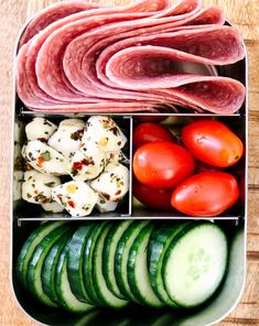 a lunch box filled with meat, tomatoes, cucumbers and other food items