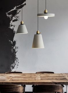 three pendant lights hanging over a wooden table