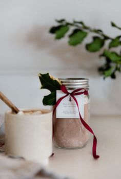 a jar filled with pink sand next to a potted plant on a white table