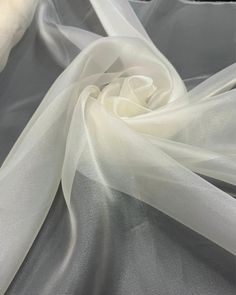 the white fabric is being used to make an elegant piece of clothing or dress material