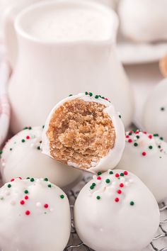 white chocolate covered donuts with sprinkles on a cooling rack next to milk