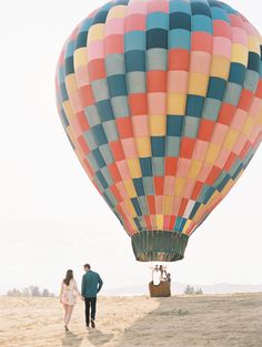 a man and woman standing in front of a hot air balloon