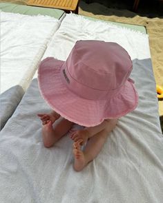 a baby wearing a pink hat sitting on top of a bed