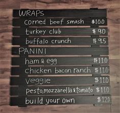 the menu for wraps is written on a wooden board with black lettering and white writing