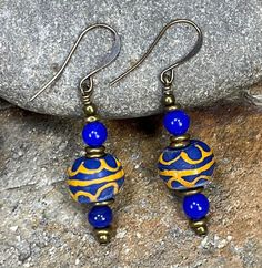 This pair of African Trade Bead Earrings are designed with blue & yellow Krobo beads from Ghana, Nigerian brass beads, and bronze ear wire hooks. They pair well with many fashion styles and accessorize both day and evening wear! Yes-I can custom design jewelry for you with the African beads I have in stock! Message me about your jewelry desires, and I'll design something just for YOU! I love creating one-of-a-kind jewelry for my clients! COUPON CODES for serious shoppers : Save 10% on purchases totaling $100 or more- enter coupon code 'SAVE10PERCENT' at checkout! Save 15% on purchases totaling $200 or more- enter coupon code 'SAVE15PERCENT' at checkout! Follow my jewelry on Facebook at "African Echoes Beads" Follow my creative life on Instagram @rodwimerfineart Krobo Beads, Small Dangle Earrings, African Earrings, African Trade Beads, Brass Beads, Yellow Earrings, African Beads, Earrings Small, Earrings Minimalist