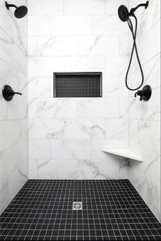 a shower with black and white tile on the floor, walls and floors is shown