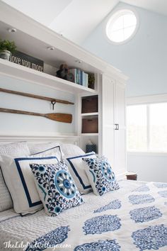 a bed with blue and white pillows on top of it in a bedroom next to a window