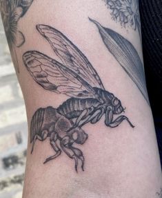 a close up of a person's arm with a tattoo on it and a bee