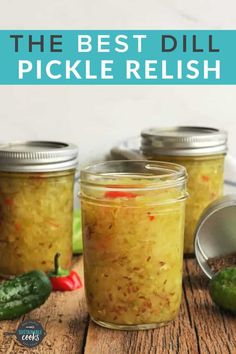 three jars filled with pickles sitting on top of a wooden table next to peppers