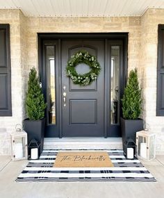 the front door is decorated with wreaths and potted plants