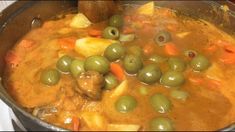 olives, potatoes and carrots are cooking in a large pot on the stove