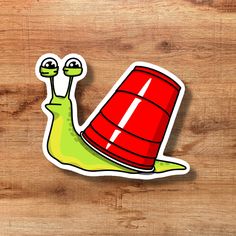 a sticker depicting a snail with a bucket on its back, sitting on a wooden surface