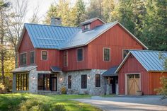 a large red barn with two garages in the middle of trees and grass around it