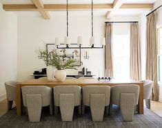 the dining room table is surrounded by beige chairs and white vases with flowers in them