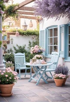 an outdoor patio with blue shutters and potted plants on the side of it