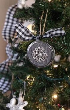 an ornament hanging from the top of a christmas tree in front of a plaid ribbon