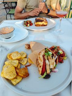 a man sitting at a table with plates of food and wine in front of him