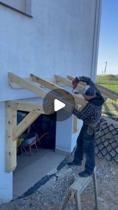 a man working on the side of a building with wood beams in front of him