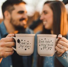 two people holding coffee mugs with words on them