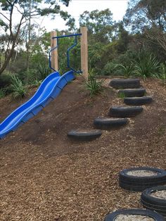 a blue slide and some black tires on the ground