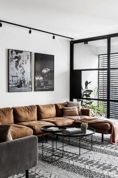 a living room with couches, tables and pictures hanging on the wall above them