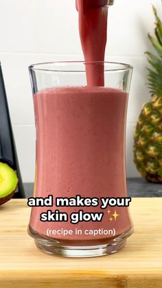 a smoothie being poured into a glass on top of a wooden cutting board with the words, and makes your skin glow recipe in caption