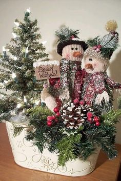 two teddy bears are sitting in a basket with pine cones and evergreens on the table