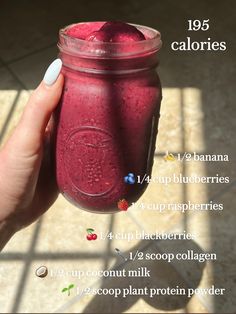 a hand holding a mason jar filled with blueberries and raspberry smoothie