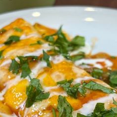 a close up of a plate of food with cheese and sauce on it, topped with green leaves