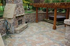 a patio with stone walls and an outdoor fireplace