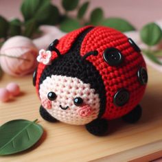 a crocheted ladybug sitting on top of a wooden table