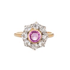 Stylish antique Edwardian pink sapphire & diamond cluster ring crafted in 14k yellow gold (circa 1900s to 1910s). One center set pink sapphire is estimated at 0.50 carats, accented with eight estimated 0.15 carat old mine cut diamonds. The total diamond weight is estimated at 1.20 carats (estimated at I-J and SI1-I1 clarity). The sapphire is in very good condition and free of cracks or chips.  The classic cluster design highlights a halo of diamonds surrounding the vibrant and lively pink sapphi Classic Pink Diamond Cluster Ring, Classic Pink Cluster Ring With Center Stone, Pink Cluster Diamond Ring With Center Stone, Classic Pink Cluster Ring With Prong Setting, Classic Pink Sapphire Ring With Rose Cut Diamonds, Heirloom Pink Sapphire Ring, Yellow Gold Diamond Ring With Rose Cut Pink Sapphire, Heirloom Pink Sapphire Ring With Center Stone, Antique Pink Diamond Rings