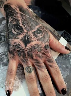 a hand with an owl tattoo on it