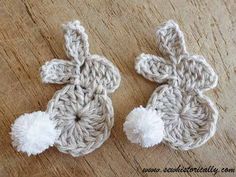 two crocheted flowers sitting on top of a wooden table