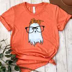 Cute Ghost with Glasses and Bandana Shirt Halloween T-Shirt Gift for Halloween Women Cute Shirt for Halloween Spooky Tee Funny T Shirt Perfect gift for friends, family, and all loved ones. Order affordable, high-quality, personalized t-shirts.  Carefully hand-printed using the latest technology printing houses and water-based ink. Thanks for choosing us.  WHAT SIZE FITS ME BEST  Please scroll through the photos. Measurements for clothing types and sizes are listed as well.  These are a unisex fi Ghost Shirt Women, Casual Halloween T-shirt With Funny Print, Cute Orange Halloween T-shirt, Trendy Halloween T-shirt With Cartoon Print, Funny Ghost, Ghost Shirt, Halloween Women, Cute Ghost, Personalized T Shirts