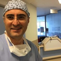 a man in scrubs and glasses is smiling at the camera