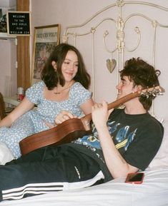 a man and woman laying in bed with an ukulele on their stomachs