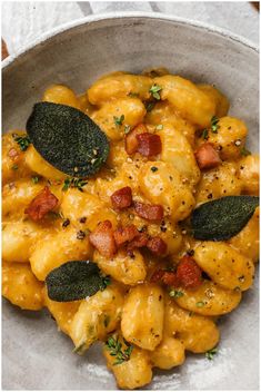 a white bowl filled with macaroni and cheese covered in spinach leaf garnish