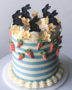 a blue and white striped cake topped with frosting rabbits