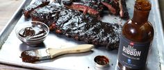 bbq ribs and barbecue sauce on a tray with a bottle of booze next to it