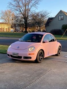 a pink car is parked on the side of the road in front of a house