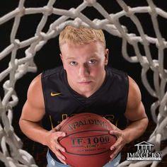 a young man holding a basketball in front of a hoop