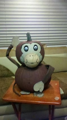 a stuffed animal sitting on top of a wooden table next to a window with blinds