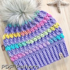 a crocheted hat with a pom - pom sitting on top of it